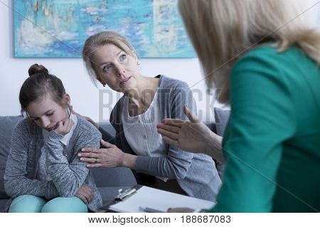 Shy teenage girl and her worried mother at psychologist's