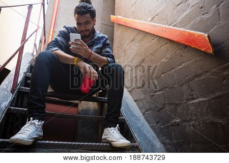 Man using mobile phone while having drink on staircase of bar