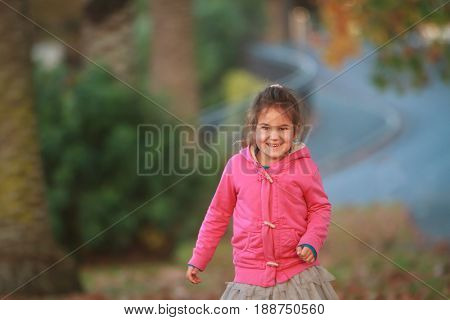 outdoor portrait of young happy child girl playing in park on natural background