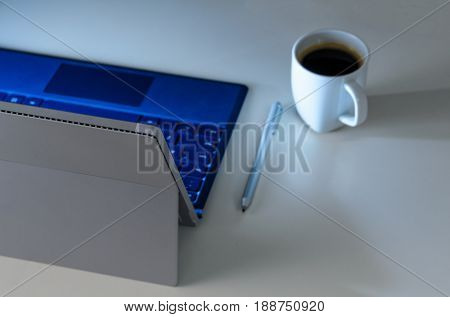 Modern laptop on evening work place, coffee cup and notebook with pen, view from above