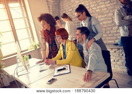 Group of young workpeople on workplace on computer together 