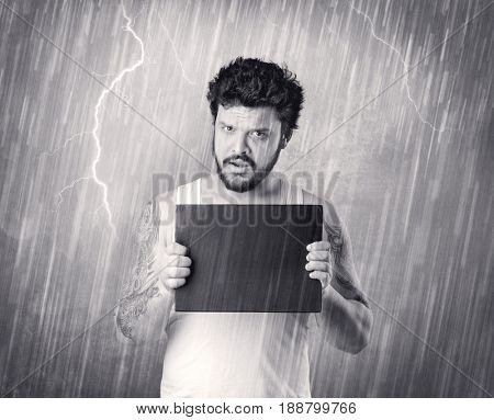 Caught gangster with rainy, grey background and black table on his hand. 