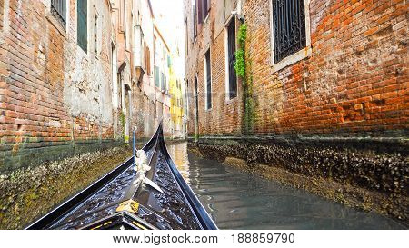 Gondola ride in canal of Venice town with colorful building along