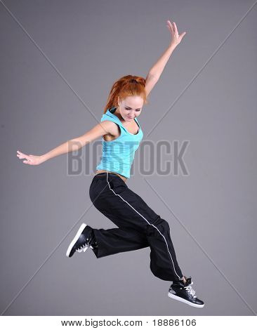 funky ung kvinna hoppa och dansa isolerade på grå bakgrund