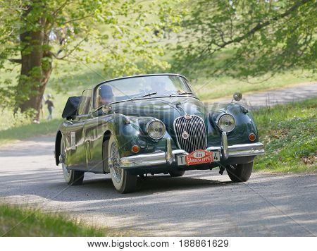 STOCKHOLM SWEDEN - MAY 22 2017: Dark green Jaguar XK 150 classic car from 1960 driving on a country road in the public race Gardesloppet in the forests at Djurgarden Stockholm Sweden. May 22 2017