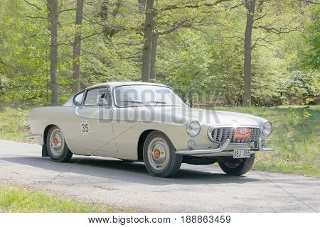 STOCKHOLM SWEDEN - MAY 22 2017: White Volvo P1800 S classic car from 1963 driving on a country road in the public race Gardesloppet in the forests at Djurgarden Stockholm Sweden. May 22 2017