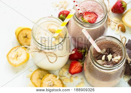 Set of milkshake in jars. Banana chocolate and strawberry milkshakes with nuts and coconut. Summer dessert. Healthy food.