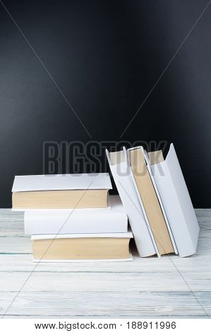 Open black and Whitel books on wooden table, black board background. Back to school. Education business concept