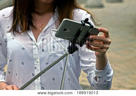 A girl is holding a smartphone on a monopod