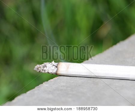 A burning cigarette on the table smokes