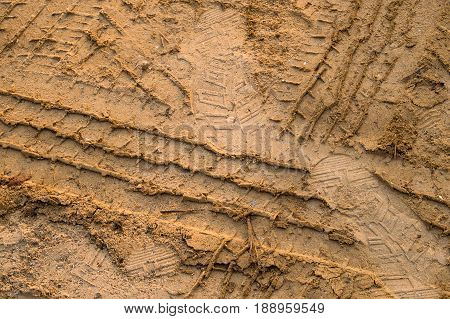 dirt road urban non asphalt traffic way with tire tracks of many type of vehicles and foot prints.