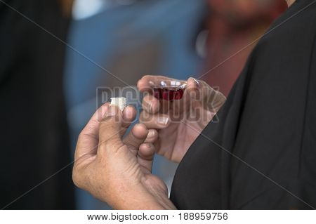 adult and faithful in Jesus Christ woman in a holy communion. pray with holding loaf and little cup of the wine.