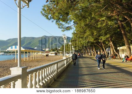 Gelendzhik Krasnodar Krai Russia - April 29.2017: People walk along the embankment of Gelendzhik on the background of mountains and alleys of pine trees in sunset