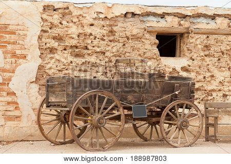 Vintage heritage horse cart standing in front of weathered mud brick wall history scene near Tucson Arizona AZ USA