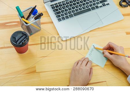 A High Angle View Of A Young Brunette Works On Her Desk With Documents And A Laptop. Entrepreneur Wo