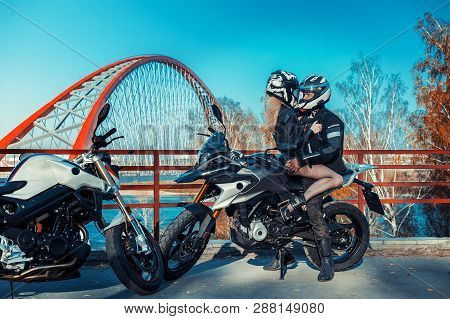 An Attractive Guy And A Young Woman In A Black Leather Outfit With A Motorcycle. Male And Female Bik