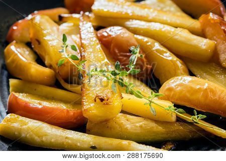 Roasted parsnips with apple and thyme, on black serving platter.