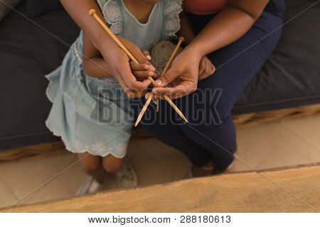 High angle view of African American grandmother teaching her granddaughter how to knitt in living room at home