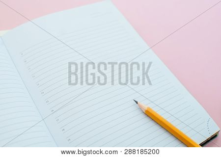 A Pencil On A Notebook In The Linel. School Supplies. White Sketch Book With Orange Pencil. Note Boo