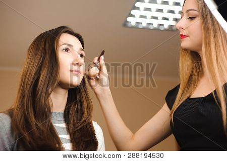 Make Up Artist Doing Professional Make Up Of Young Woman. Beauty Shcool