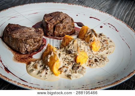 Closeup Two Pieces Of Grilled Meat Steak With Blood With Potato Zrazy