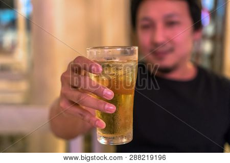 Closeup Hand Holding Glass Of Beer From Asian Young Man In Happiness Action In Pub And Restaurant Wi