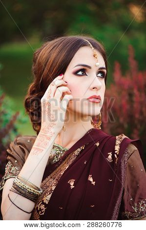 Portrait Of Beautiful Indian Girl. Young Hindu Woman Model With Tatoo Mehndi And Kundan Jewelry. Tra