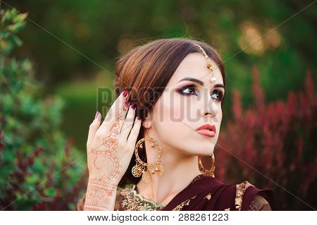 Portrait Of Beautiful Indian Girl. Young Hindu Woman Model With Tatoo Mehndi And Kundan Jewelry. Tra