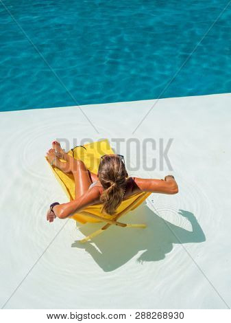 Woman sitting sunbathing on a transat at the swimming pool