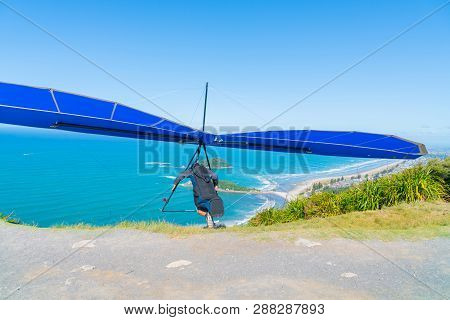 Take-off Hanglider Pilot Runs At Slope With Scenic Beaches Of Mount Maunganui Below.
