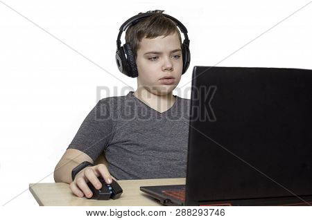 Technology, Gaming And People Concept - Boy In Headphones Playing Video Game On Laptop Computer At H