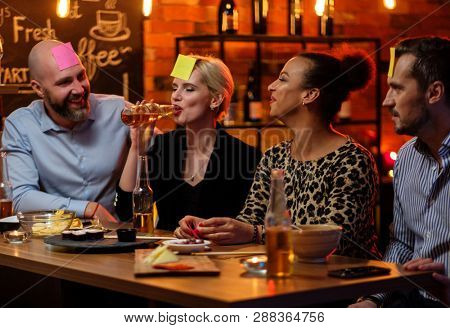 Group of friends playing sticky head game behind bar counter in a cafe