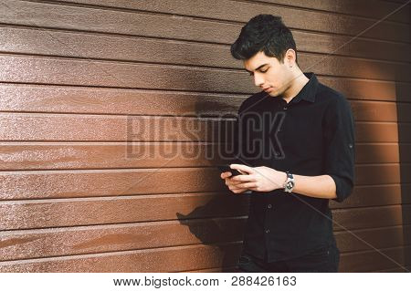 Portrait Of Young Handsome Turkish Male Model. Mediterranean Race Brunette In Black Shirt Is Using A