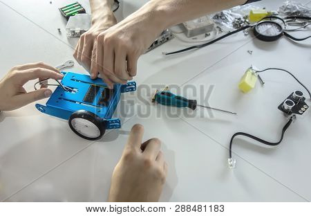 Top View Close-up Hands Of Students Collecting On A White Table Design Of The Future Robot. Robotic,