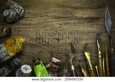 Old Paint Tubes And Brushes On Wooden Background