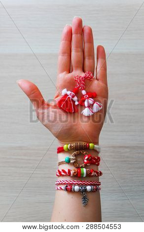 Bulgarian Traditional Spring Decor Martenitsa Bracelets, Holding In Hand, Wooden Background. Baba Ma