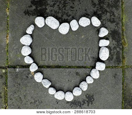 Heart Of Stone Made Of Small White Stones On The Dark Stone Background.