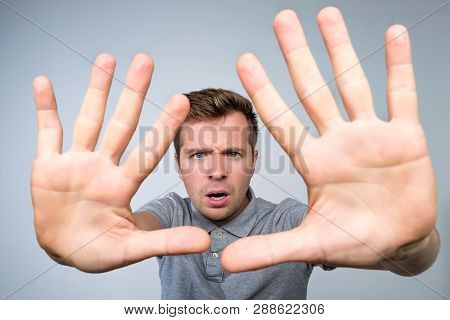 Young European Man In Gray T-shirt Showing With Hand Stop Timeout Gesture.