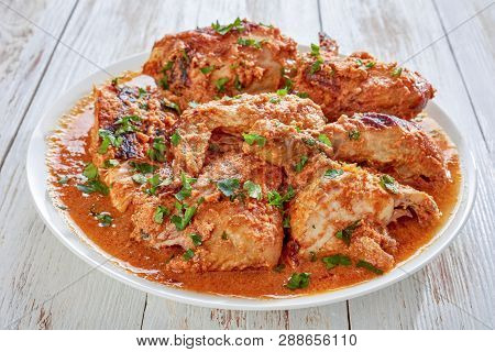 Chicken Stewed In Creamy Spicy Coconut Gravy, Kuku Paka, Served On A White Plate On An Old Wooden Ta
