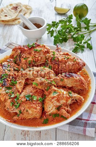Chicken Stewed In Creamy Spicy Coconut Milk Gravy, Kuku Paka, Served On A White Plate On An Old Wood