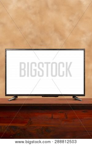 Vertical Shot Of A Blank Large Screen Tv With Copy Space On Table.  Brown Muddled Background.