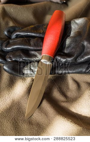 Knife And Leather Gloves. A Sharp Hunting Knife.