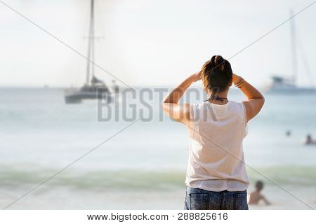 Women Looking To Yacht Faraway Sailing The Sea In The Sunset.