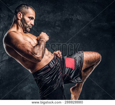 Professional Muay Thai Boxer Showing Kick Fighting Technique. Studio Photo Against A Dark Textured W