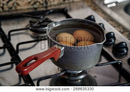 Boiled Eggs In Dipper Of Water On The Kitchen Stove.