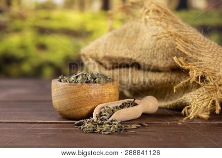 Lot Of Pieces Of Dry Green Tea With Wooden Bowl In A Forest