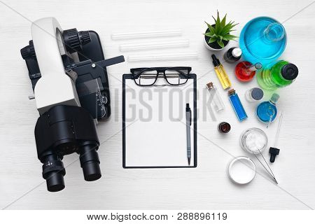 Laboratory Table With A Blank Paper Sheet Of Researching Results, Microscope And A Chemical Reagent 
