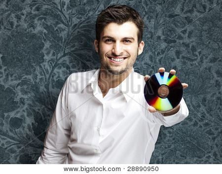 portret młodego mężczyzny przystojny przytrzymanie cd przed ściana