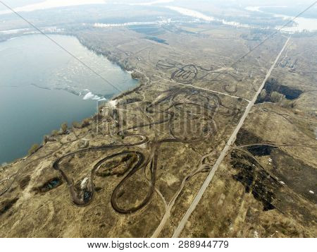 Curved pattern of dirt road, similar to the lines drawing geoglyphs of the Nazca desert.Aerial view of the countryside (drone image).Near river Desna.. March8, 2019.Near Kiev,Ukraine