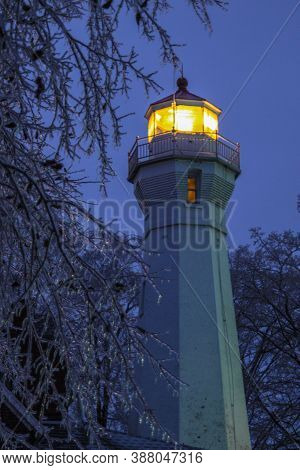 Illuminated Beacon Of The Port Sanilac Lighthouse Surrounded By Icicles On A Cold Winter Night.
